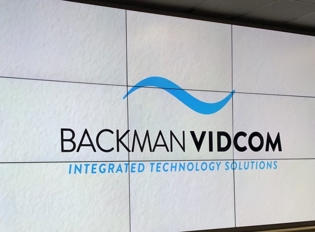 Backman Vidcom logo displayed across a multi-panel video wall installation